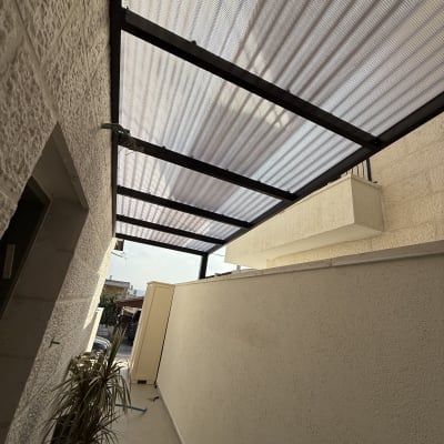 גג פרגולה עם קורות מתכת ומחיצות צד