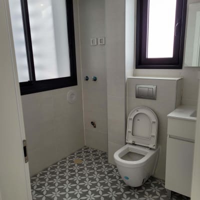 אסלה פתוחה בחדר אמבטיה עם אריחים מעוצבים