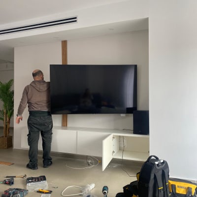 איש מקצוע מתקין טלוויזיה עם כלים על הרצפה