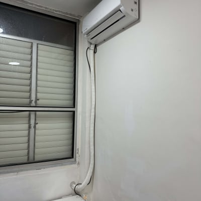 מזגן מותקן על קיר לבן עם צינור חיבור