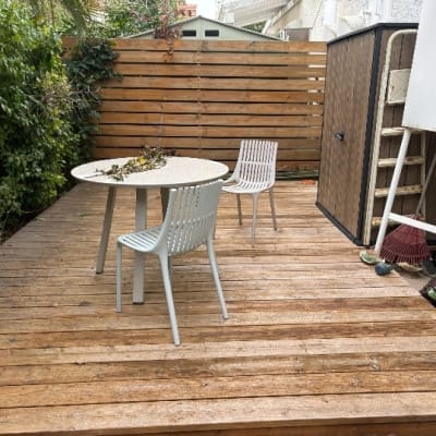 דק עץ עם שולחן וכיסאות בגינה