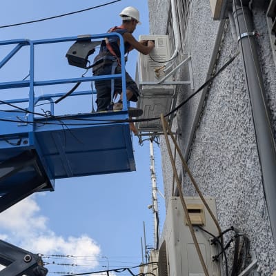 טכנאי מתקין מזגן על קיר חיצוני עם מנוף