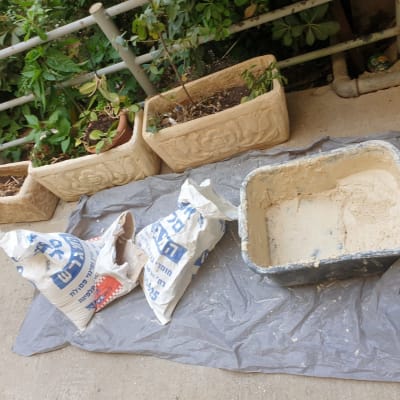 שקיות חומרי בניין ומיכל עם תערובת על יריעת פלסטיק