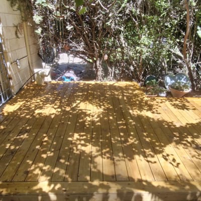 דק עץ בגינה עם עציצים מסביב