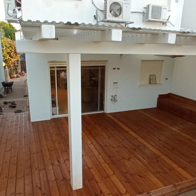 דק עץ חדש בחצר עם פרגולה לבנה