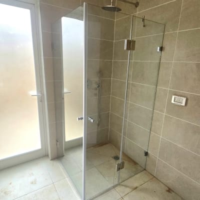 מקלחון זכוכית בחדר אמבטיה עם אריחים בהירים