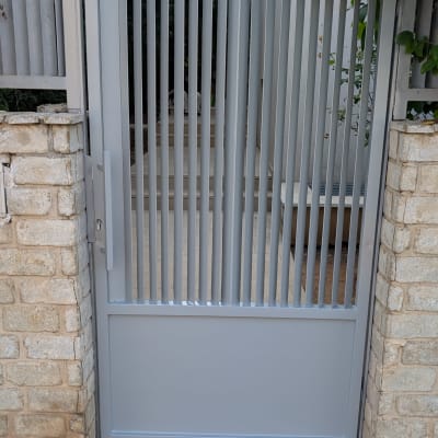 שער מתכת אפור עם קירות אבן מסביב