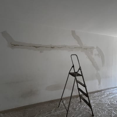 קיר עם תיקוני טיח וסולם בחדר ריק