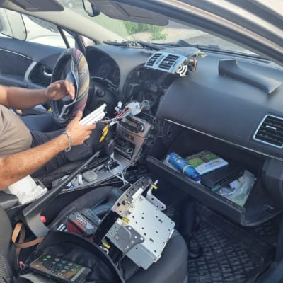 אדם מתקין מערכת מולטימדיה ברכב עם חוטים חשופים