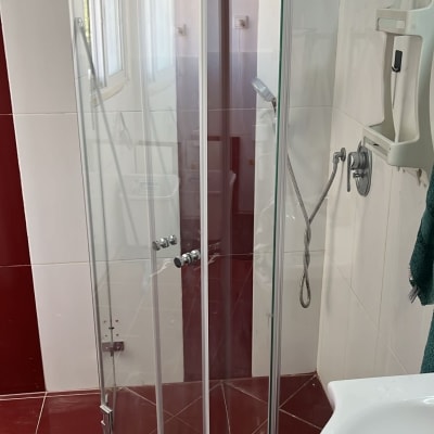 מקלחון זכוכית עם ראש מקלחת וכיור בחדר אמבטיה