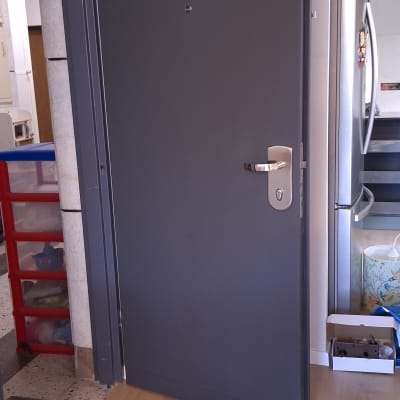 דלת מתכת אפורה עם ידית כסופה פתוחה למחצה