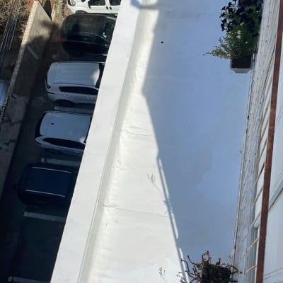 גג אטום עם צמחייה מסביב, צל של אדם על הגג