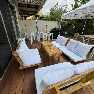 ריהוט גן עם ספות לבנות ושולחנות עץ תחת פרגולה