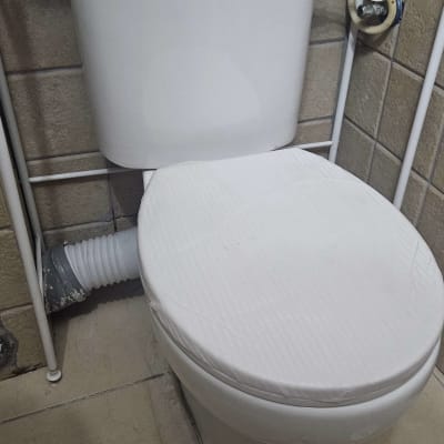 אסלה עם חיבורי צנרת בחדר אמבטיה