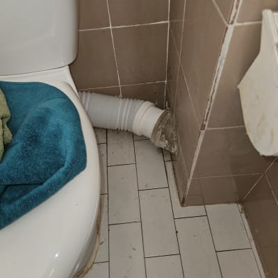 אסלה עם צינור פלסטיק גמיש מחובר לקיר