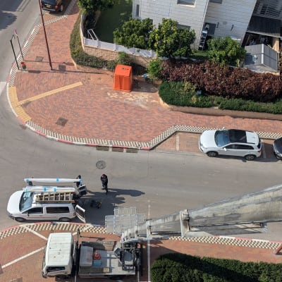 מנוף מתרומם מעל רחוב עם רכבים חונים