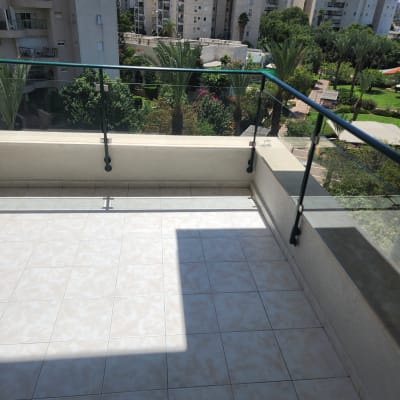 מרפסת נקייה עם רצפת אריחים ומעקה זכוכית.