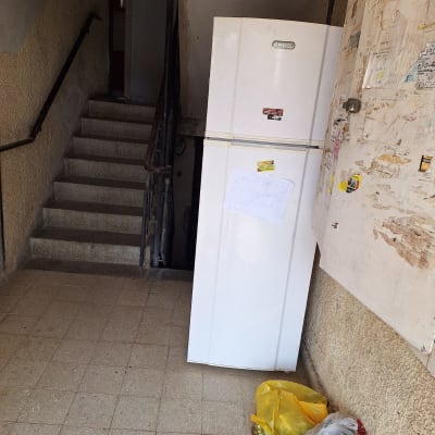 מקרר לבן עם שלט, שקיות עם מוצרים על הרצפה