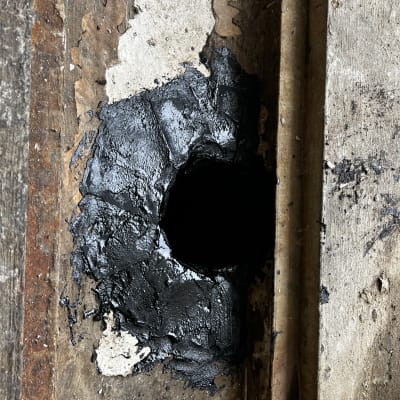 חומר איטום שחור על קיר עץ ישן