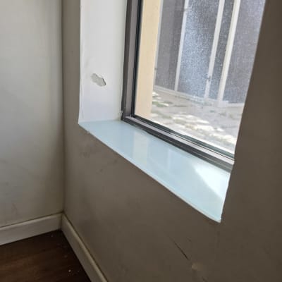 חלון עם אדן זכוכית ופינה פגומה בקיר