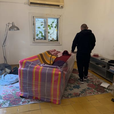 ספה עטופה בניילון בחדר עם אדם עומד ליד