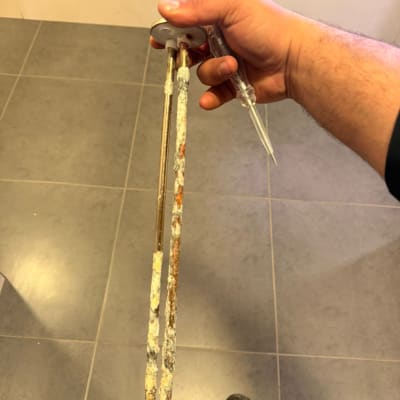 יד מחזיקה גוף חימום עם קורוזיה על רצפה אפורה