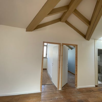 קירות גבס לבנים עם דלתות עץ ותקרה משופעת