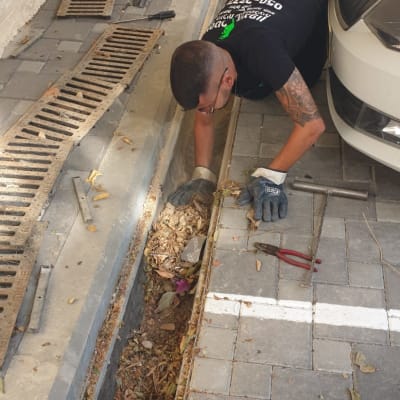 אדם מנקה תעלה עם עלים וכלים