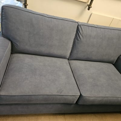 ספה כחולה עם ריפוד מרופד ושתי כריות מושב