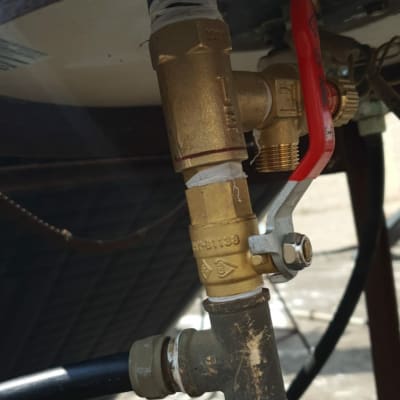 שסתום פליז עם ידית אדומה וצינורות מחוברים