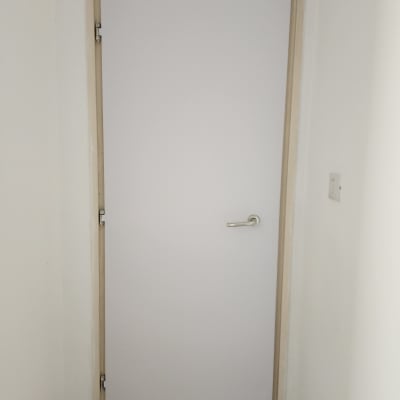 דלת לבנה עם ידית מתכת בחדר קטן
