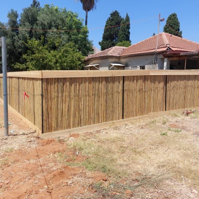 גדר עץ גבוהה מקיפה גינה עם אדמה יבשה