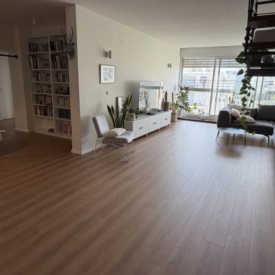 סלון דירה מרווח עם התקנת פרקט בגוון עץ טבעי