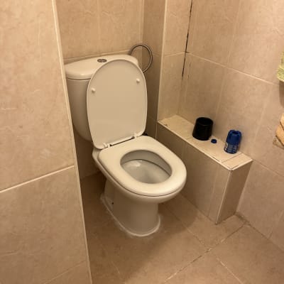 אסלה בחדר אמבטיה עם כלים על המדף