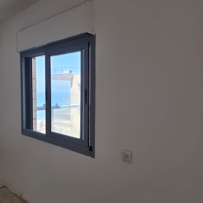 קיר עם חלון כחול ונוף חיצוני