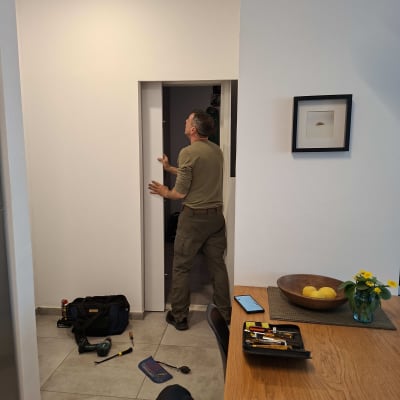 אדם עובד על דלת עם כלים על הרצפה