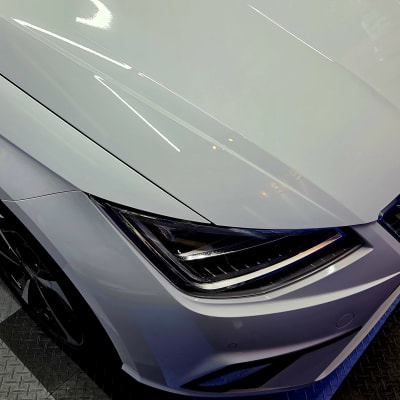 מכונית לבנה על רצפת מוסך עם ציוד דיטיילינג