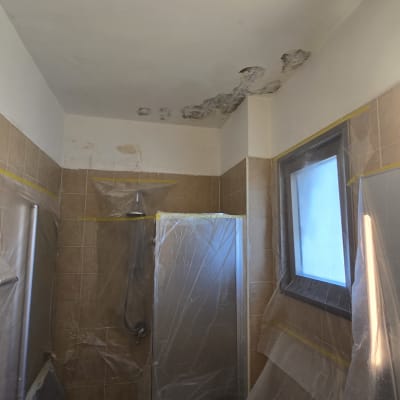 חדר אמבטיה עם קירות מתקלפים וציוד מכוסה בניילון