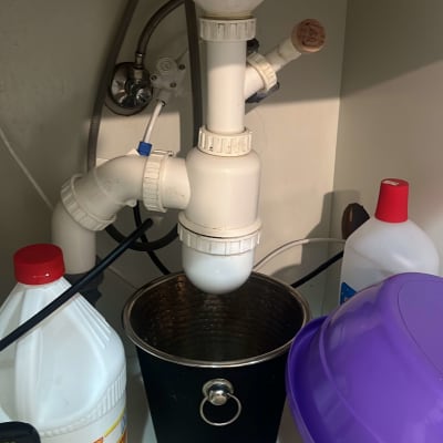 צנרת מתחת לכיור עם דלי וכלי ניקוי