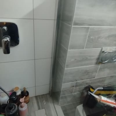 מוצרי טיפוח על מדף במקלחת עם אריחים אפורים