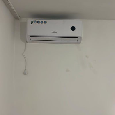 מזגן מותקן על קיר לבן עם כבל חשמל