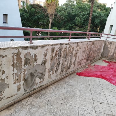 קיר מתקלף עם יריעות פלסטיק אדומות על הרצפה