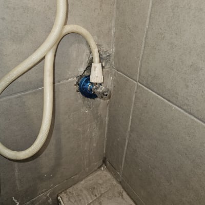 צינור מים מחובר לברז בקיר אריחים אפור