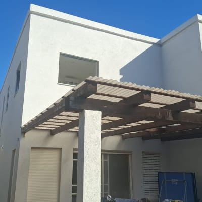 פרגולה מעץ צמודה לבית עם חלונות סגורים