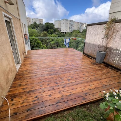 דק עץ חדש במרפסת עם עציצים מסביב