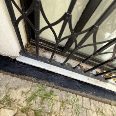 איטום שחור מתחת לחלון עם סורגי מתכת