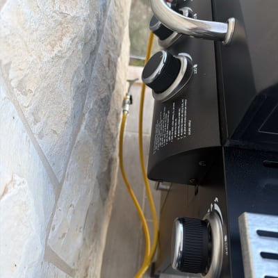 גריל גז עם כפתורי שליטה וצינור גז צהוב