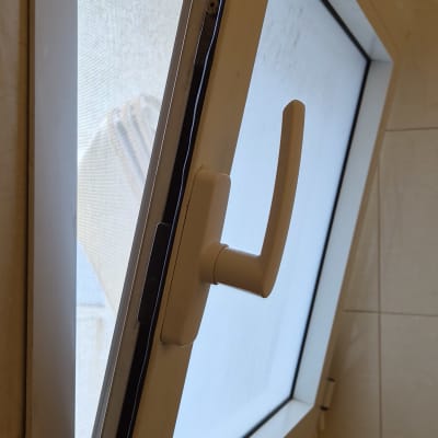 חלון פתוח עם ידית לבנה בחדר אמבטיה