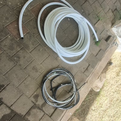 צינורות לבנים ושחורים מונחים על רצפה מרוצפת