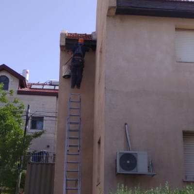 אדם על סולם מסיר יונים מגג הבית